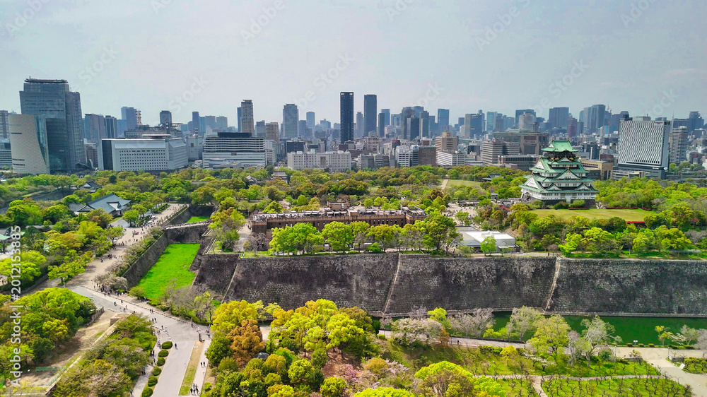 Naklejka premium Majestic Osaka Castle surrounded by modern skyscrapers from above