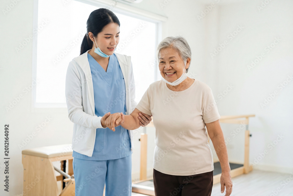 Fototapeta premium Medical assistant providing support to an elderly asian woman during physical therapy