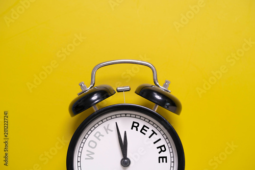 Work retirement concept with alarm clock on yellow background, symbolizing retirement planning, career transition, pension savings, work life balance and future financial freedom preparation