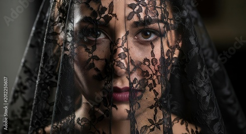 Mysterious woman peers through a delicate black lace veil covering her face.