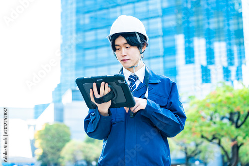 タブレットを持つ作業着を着た男性
