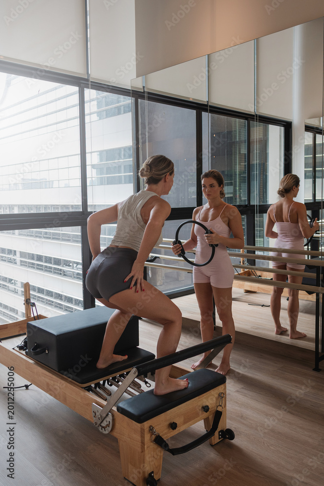 Fototapeta premium Pilates instructor guiding woman through standing reformer exercises in modern studio