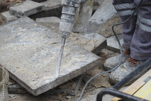 Valokuva Construction worker uses jackhammer on pavement in a city
