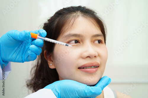 Bild auf Leinwand Asian woman receiving lip contouring procedure augmentation performed on face