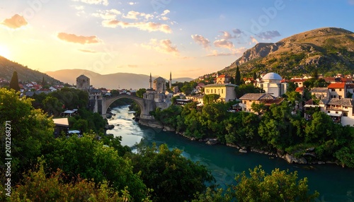 A scenic vista of a historic bridge over a river, with buildings nestled along the water's edge and mountains in the background