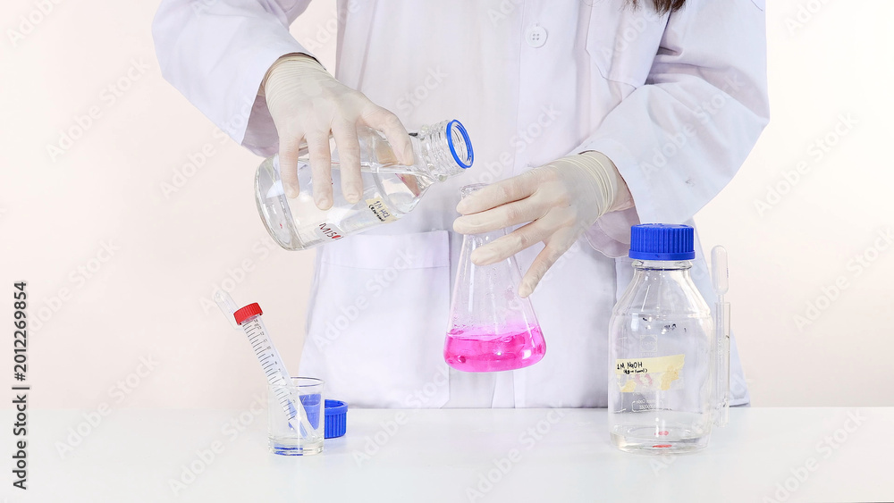 Fototapeta premium Scientist Pouring Clear Liquid into Flask with Pink Phenolphthalein Solution