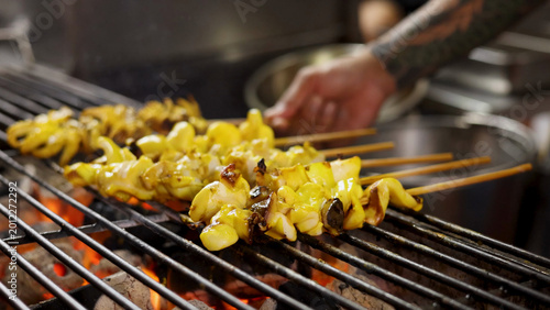 Photos Close-up of Yellow Squid Skewers Grilling Over Open Charcoal Flame