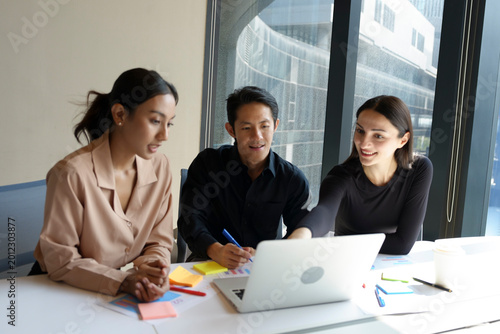 Schilderij op canvas A group of multi-ethnic young professionals, aged 20-30, working together around a laptop in a bright office with large windows