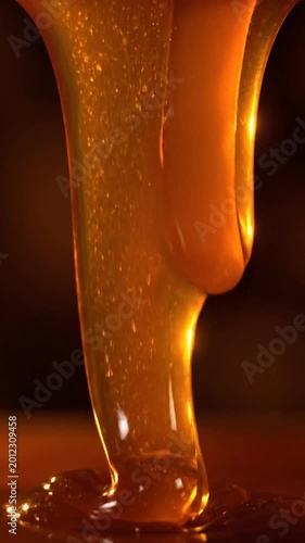 Viscous golden liquid slowly dripping and flowing in a thick stream