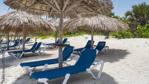 Photography Rows of sun loungers under straw umbrellas on a sandy beach