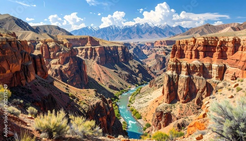 A scenic vista of a vibrant canyon carved by a winding river, backed by distant snow-capped peaks under a bright, clear sky