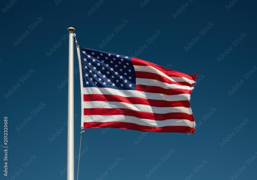 Obraz premium National flag of the United States billowing on a flagpole against a clear blue sky for patriotic campaigns, political advertising and national holiday celebrations