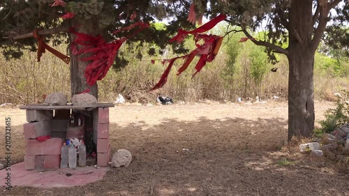Roadside Gauchito Gil Shrine with Red Flags and Offerings in Rural Argentina