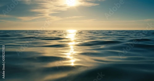 Serene ocean view at sunset with gentle waves reflecting sunlight, tranquil atmosphere