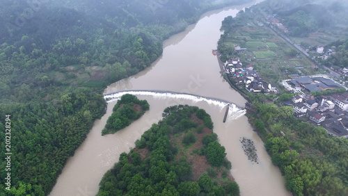 Foto Aerial view of a river with a weir dam flanked by villages and lush green forest