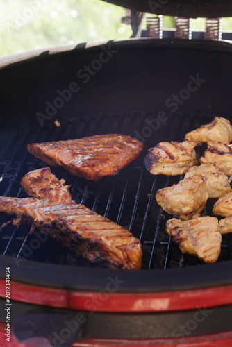 Various pieces of meat and fish cooking on a charcoal grill