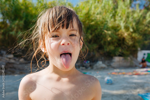 Photos Playful Young Girl Sticking Out Tongue at Beach During Summer Vacation