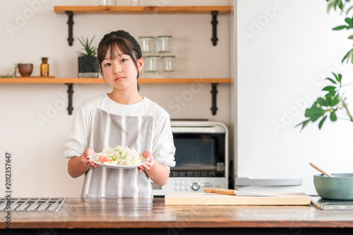 A child/girl/kid holding vegetables in the kitchen (distressed/dislikes vegetables/picky eaters)
