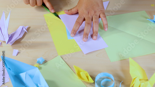 Photos Person Cutting Colored Paper with a Craft Knife on a Wooden Desk