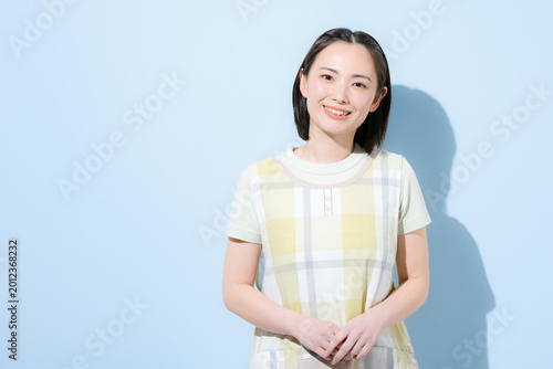 水色背景で保育士や介護士お母さんなど、働く女性のカメラ目線の笑顔　転職や求人のイメージ