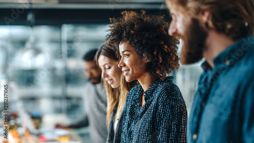 Marketing agency team collaborating in a modern office with panoramic city view through large windows, analyzing research results and reviewing printed sales statistics reports.