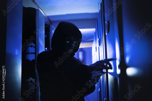Obraz na plátně Suspicious, person and hacking with tablet in server room for coding, cyberattack and data breach
