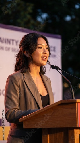 Professional woman speaking at a podium during an outdoor event