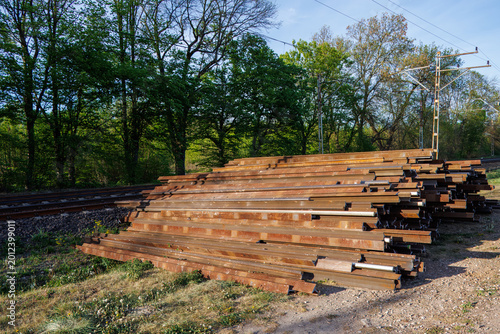 Vászonkép A pile of heavy steel railway rails lying next to a railway line under renovation