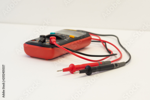 Photography A multimeter with test probes lies on a white background.