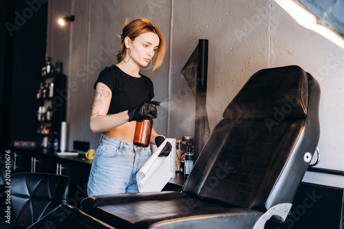 Foto Tattoo artist cleaning chair with disinfectant spray