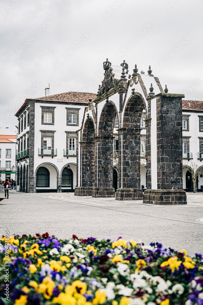 Fototapeta premium Historic stone arches in plaza with flowers in foreground