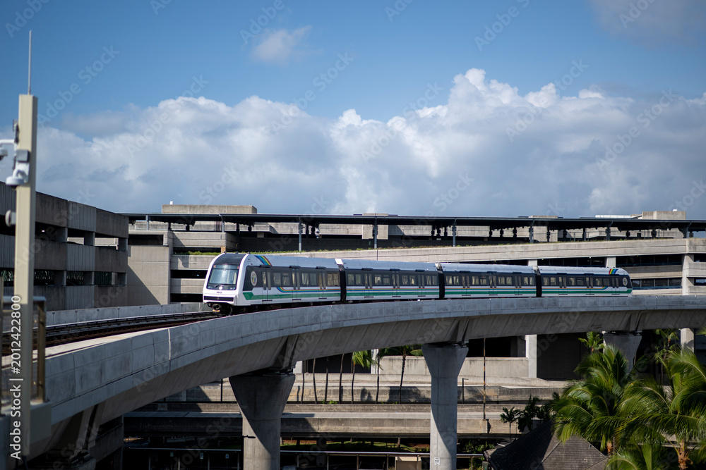 Obraz premium Honolulu Skyline Rail Train Curving Past Airport Parking Structure