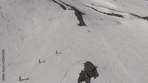 Aerial view of hikers walking across the snow-covered volcanic slopes near Rifugio Sapienza in Nicolosi, Sicilia, Italy.