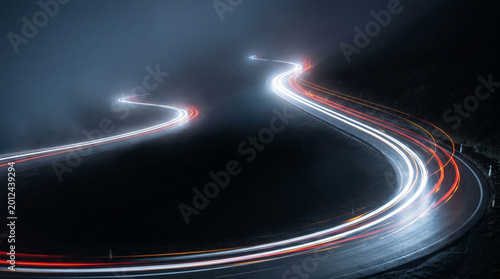 Light trails on a winding road at night, creating a sense of speed and motion