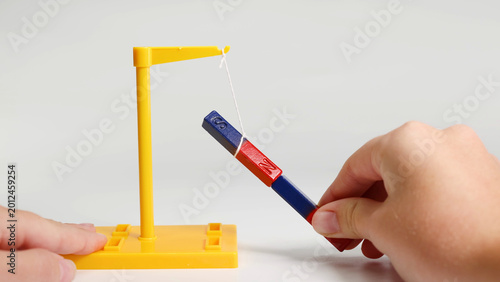 Konstfotografi Hands Demonstrating Magnetic Attraction and Repulsion Using Suspended Bar Magnet
