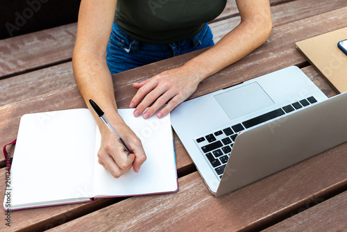 Woman freelancer writing in notebook during remote work