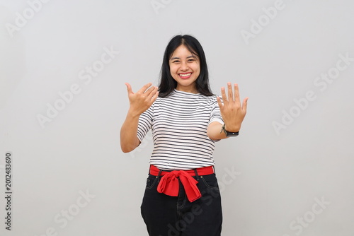 Cuadro en lienzo A young woman uses a hand gesture to call come here with her palms outstretched in a welcoming pose, a cheerful expression, isolated on a white background