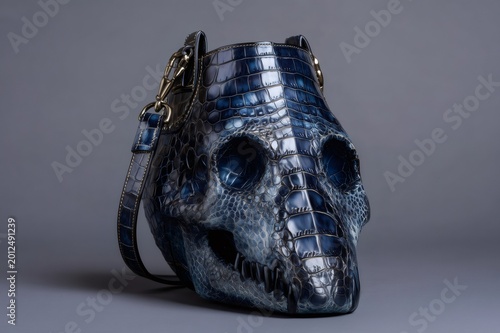 Unique blue skull shaped handbag featuring glossy crocodile texture. Luxurious fashion accessory for edgy and stylish appeal