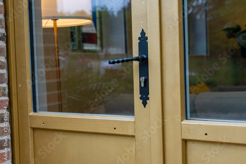 Détail d’une porte vitrée en bois avec poignée en ferronnerie dans une rénovation au style traditionnel.