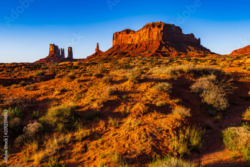 The red rock desert and spires of Monument Valley Navajo Tribal park in Arizona United States of America in strong morning sunrise sunlight.