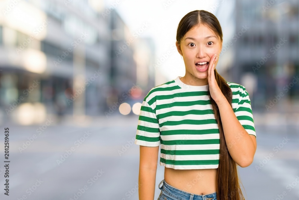 Obraz premium Young asian woman expressing excitement and surprise, touching her face outdoors