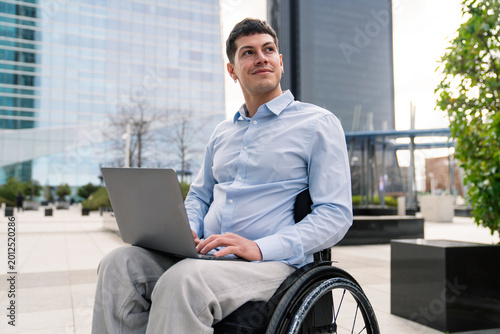 Obraz na plátně Professional man working on a laptop while sitting in a wheelchair, reflecting m