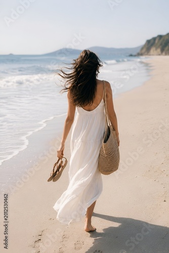 Young woman walking barefoot on a sandy beach at sunset