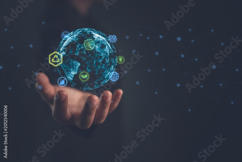 Obraz na plátně Business person holding a glowing digital globe surrounded by green energy and c