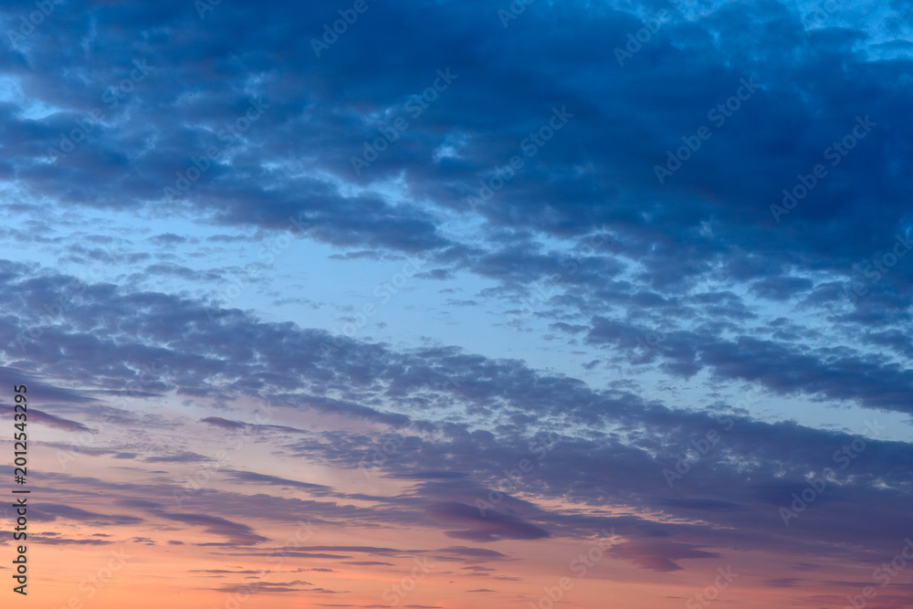 Obraz premium Beautiful evening sky panorama with textured clouds illuminated by colorful sunset gradients and fading daylight