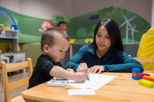 Slika na platnu Mother and son drawing together with crayons on paper at table