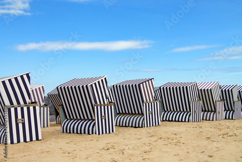 Foto A row traditional striped beach chairs from the wind strandkotb on a sandy beach on the Baltic coast