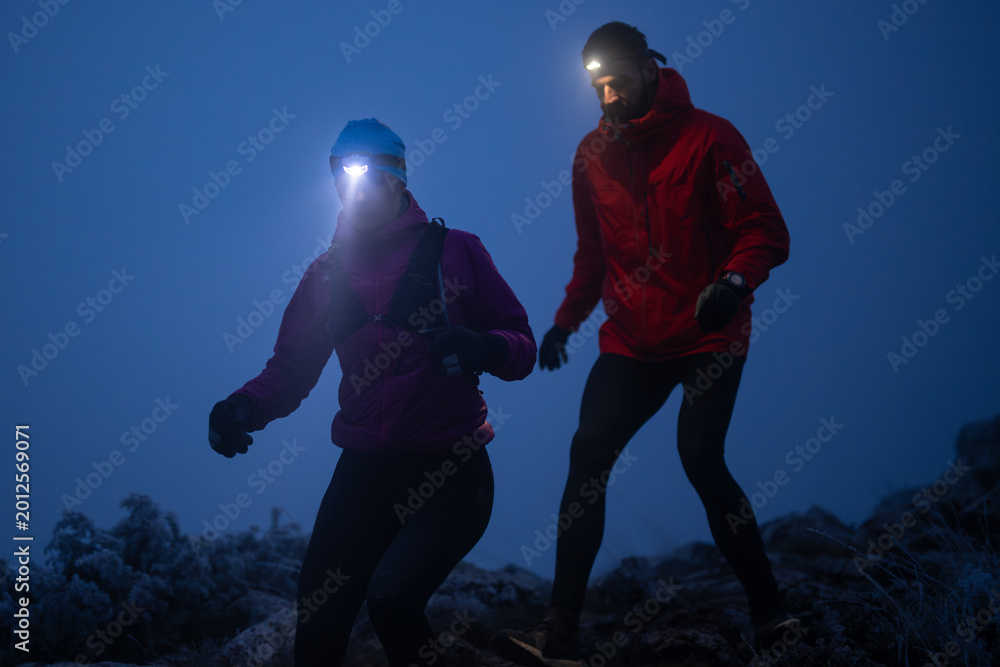 Fototapeta premium Night Trail Running Couple With Headlamps On Frosty Mountain Path Training Together