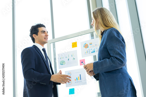 Man and woman businesspeople planning business strategy while looking at infographic on wall. Business, education and office concept.