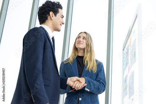Man and woman businesspeople planning business strategy while looking at infographic on wall. Business, education and office concept.
